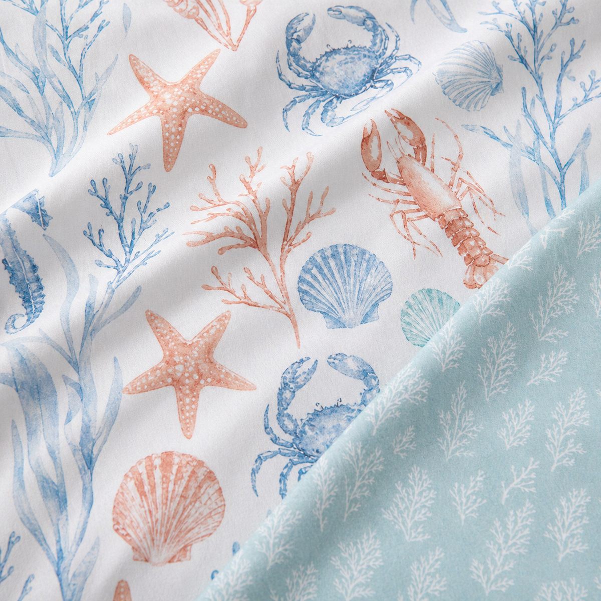 Macro close-up of the Coastal Bay polycotton duvet fabric with coral and blue sea life print