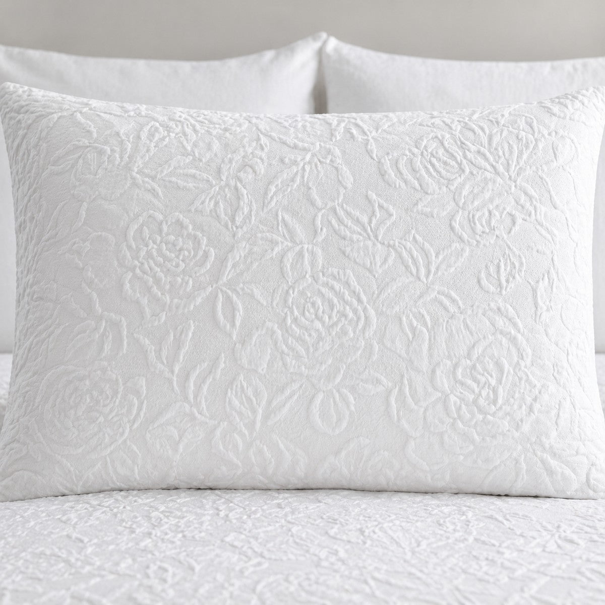 Close-up of a white Collier jacquard floral pillowcase showing the raised textured pattern