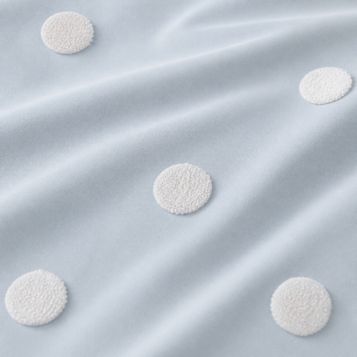 Macro close-up of the duck egg cotton fabric and raised white dots on the Dot Garden duvet cover