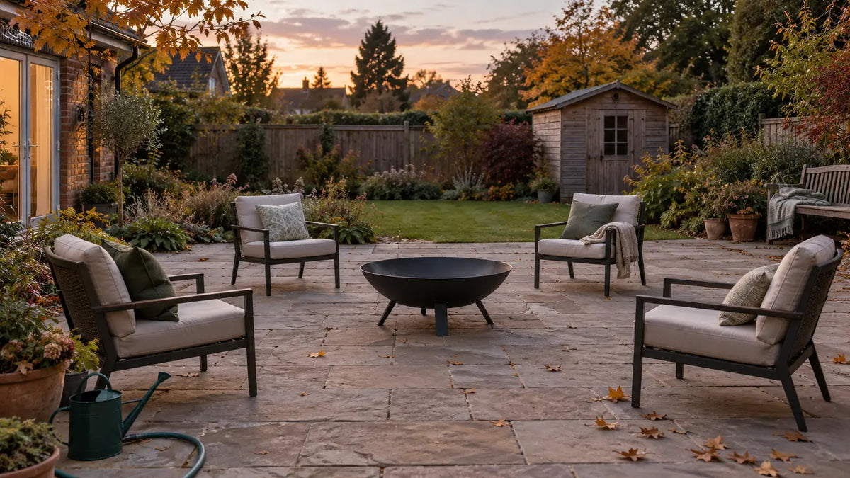 Unlit fire pit on an open stone patio with seating moved back and a hose ready
