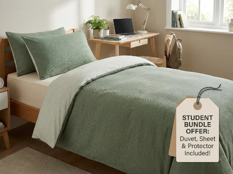 A bed dressed in a sage green duvet cover and matching pillowcases, shown in a styled bedroom scene with a wooden desk, lamp, window, and backpack. A hanging tag reads 'STUDENT BUNDLE OFFER: Duvet, Sheet & Protector Included!'.