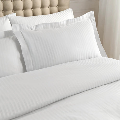 White bed sheets and pillows on a neatly made bed with a beige headboard.