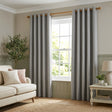 Living room with gray curtains, beige sofa, and a small table with decor items.