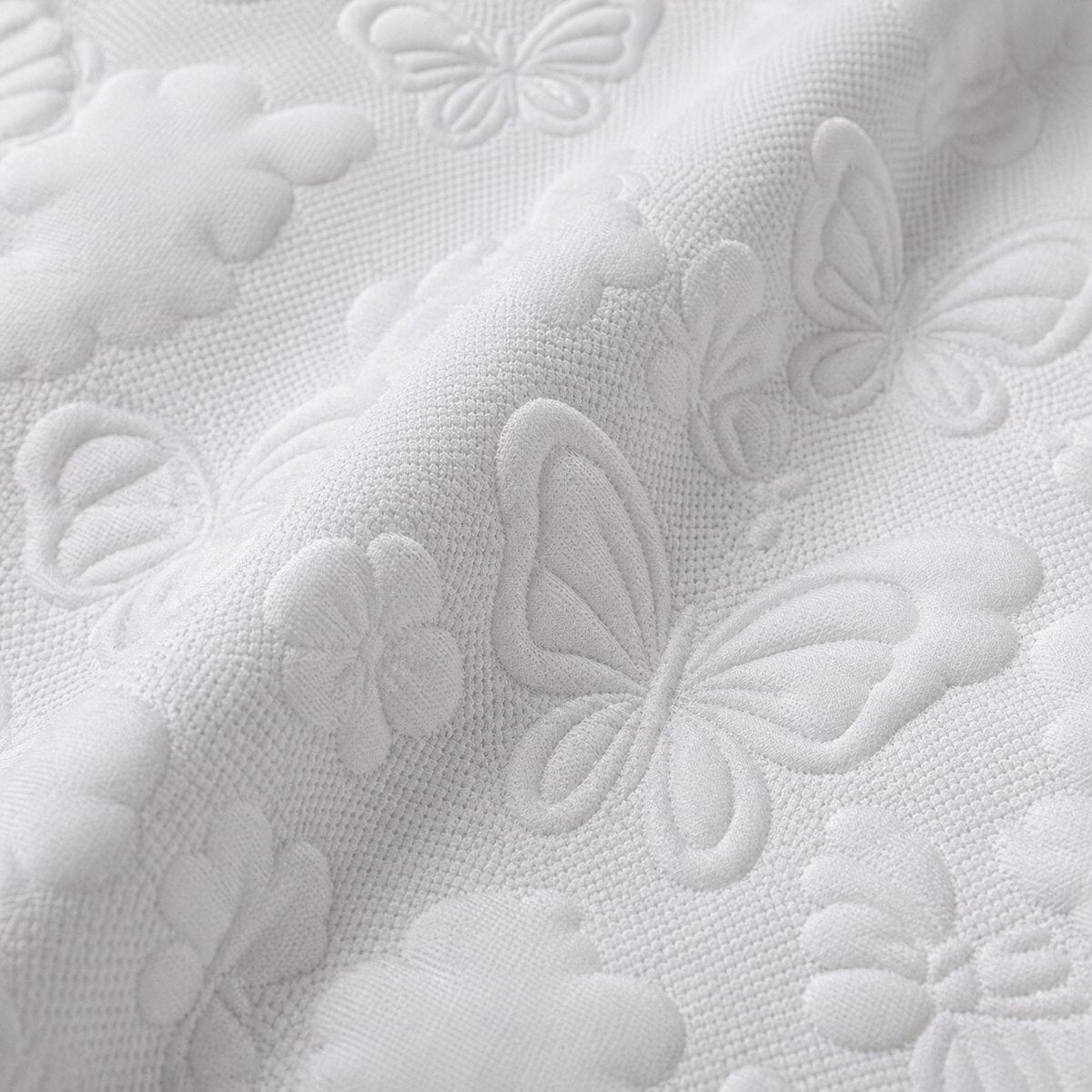 Macro close-up of white microfibre fabric with raised butterfly and floral texture