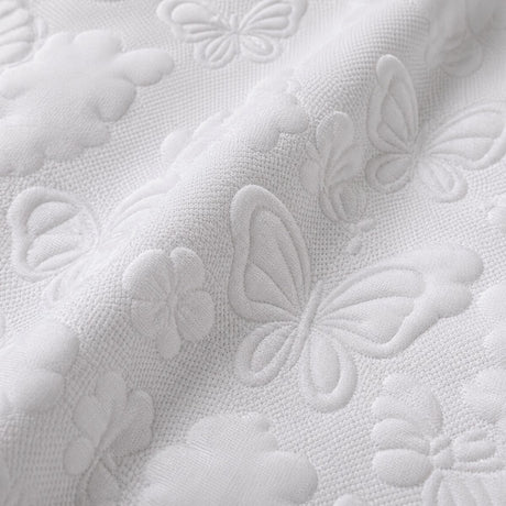 Macro close-up of white microfibre fabric with raised butterfly and floral texture