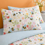 Close-up of Buzzy Bee pillowcases showing bees flowers strawberries and pale blue reverse