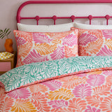 Close-up of Carmen Pink cotton pillowcases with coral leaf print and teal reverse duvet detail