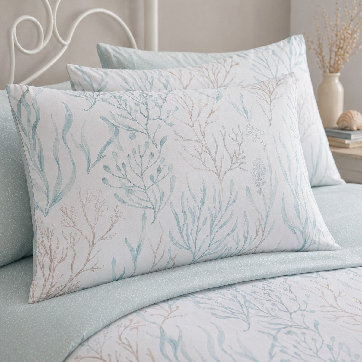 Close-up of Cora sea foam pillowcases showing coral branch and seaweed print detail