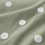 Macro close-up of the sage cotton fabric and raised white dots on the Dot Garden duvet cover