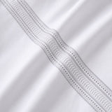 Macro close-up of white cotton fabric with the silver embroidered ladder band detail