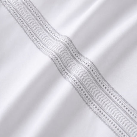 Macro close-up of white cotton fabric with the silver embroidered ladder band detail