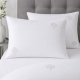Close-up of white cotton pillowcases with delicate grey embroidered tree motifs