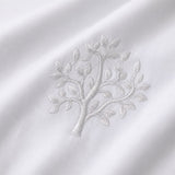 Macro close-up of white cotton fabric with raised grey embroidered tree detail