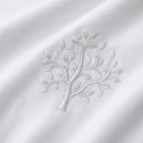 Macro close-up of white cotton fabric with raised grey embroidered tree detail