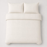 Overhead flat lay of the Laurence Llewelyn-Bowen Emile Microfibre Duvet Cover Set in cream with two matching pillowcases