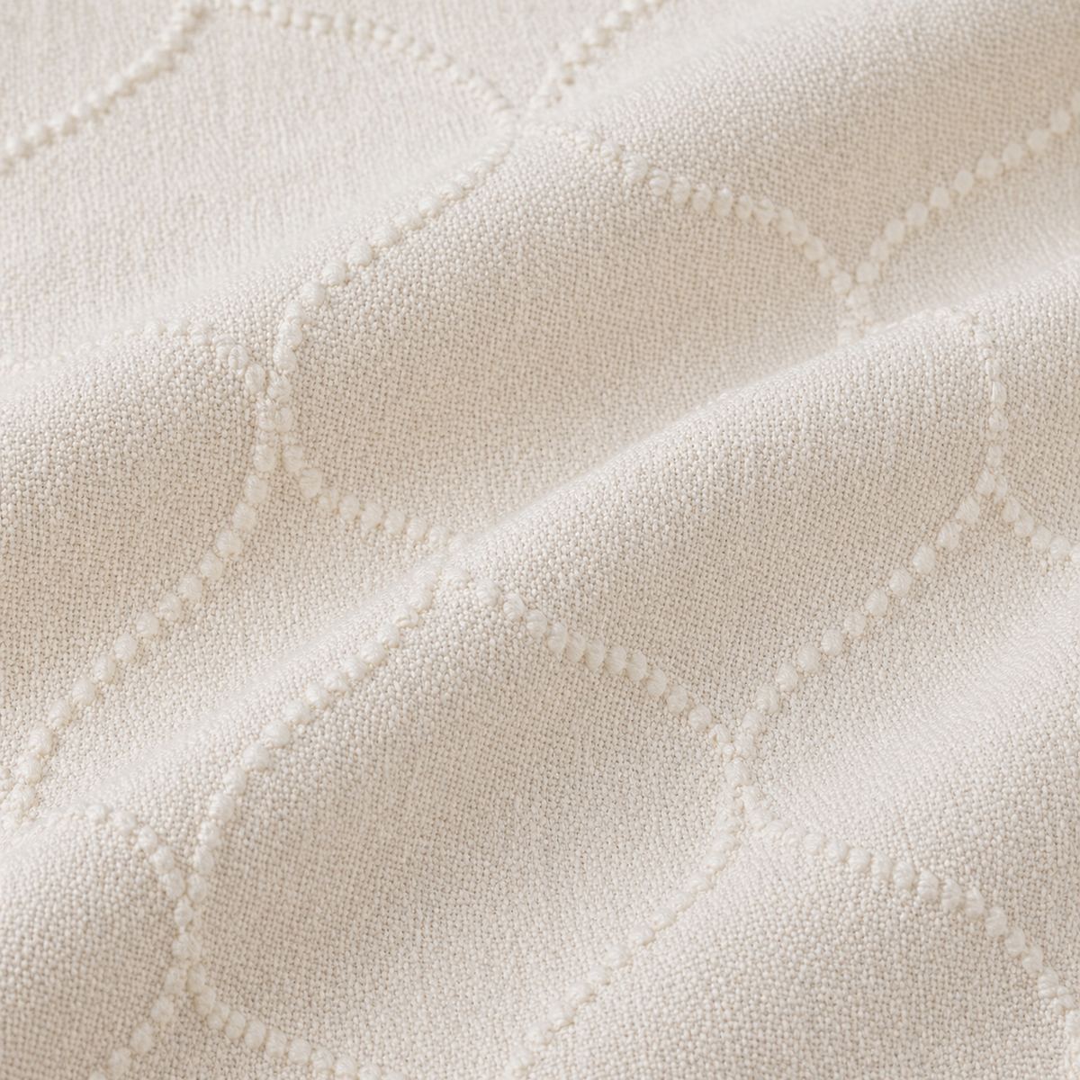 Macro close-up of the beige Montez jacquard duvet cover fabric with raised woven ogee pattern