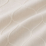 Macro close-up of the beige Montez jacquard duvet cover fabric with raised woven ogee pattern