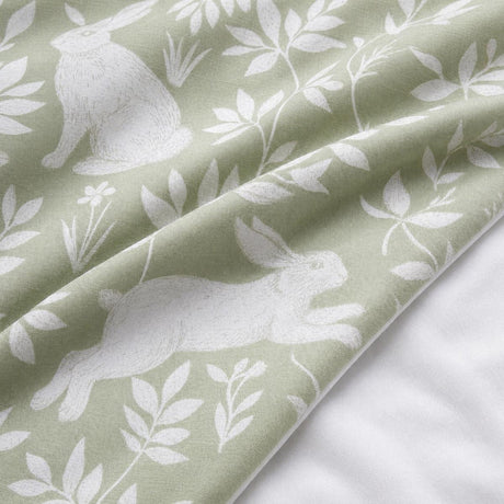 Macro close-up of the Spring Rabbits green polycotton duvet fabric with rabbit and leaf detail