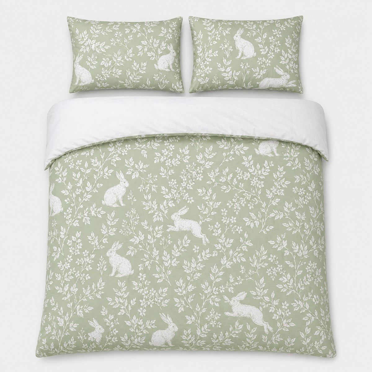 Overhead flat lay of the Spring Rabbits green reversible duvet cover set with two pillows
